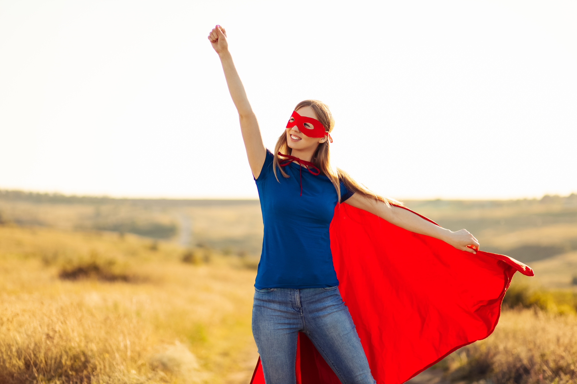 Superhero Woman. a Young and Beautiful Blonde in the Form of a Superheroine in a Red Cloak Is Growing Forward and Upward